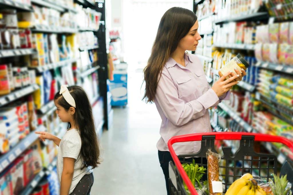 Femme avec sa fille au supermarché qui regarde la composition d'un produit